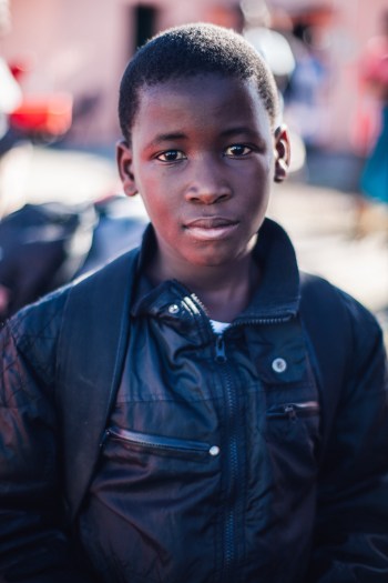 An adolescent boy with a thoughtful, open, questioning expression looks into the camera